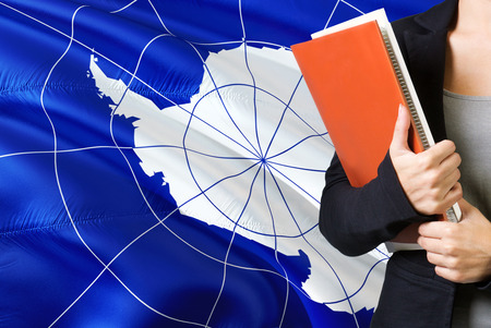 Learning language concept. Young woman standing with the Antarctica flag in the background. Teacher...