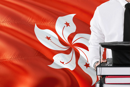 Successful student education concept. Holding books and graduation cap over Hong Kong flag background.の写真素材
