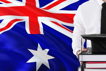 Successful student education concept. Holding books and graduation cap over Heard Island and Mcdonald Islands flag background.の写真素材