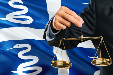 Judge is holding golden scales of justice with Martinique waving flag background. Equality theme and legal concept.の写真素材