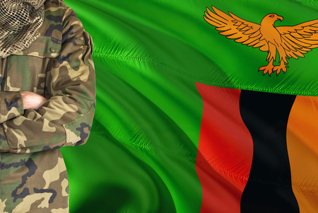 Crossed arms Zambian soldier with national waving flag on background - Zambia Military theme.の写真素材