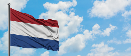 Netherlands flag waving in the wind against white cloudy blue sky. Diplomacy concept, international relations.の写真素材
