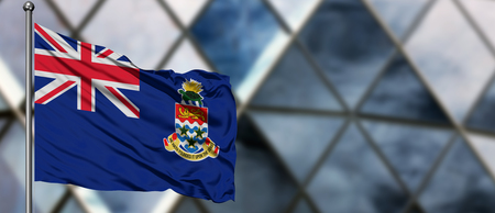 Cayman Islands flag waving in the wind against blurred modern building. Business concept. National cooperation theme.の写真素材