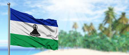 Waving Lesotho flag in the sunny blue sky with summer beach background. Vacation theme, holiday concept.の写真素材