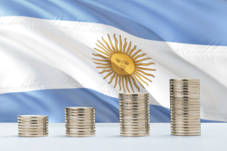 Argentina flag waving in the background with rows of coins for finance and business concept. Saving money.の写真素材