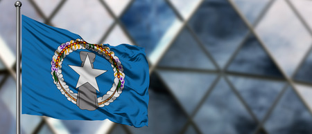 Northern Mariana Islands flag waving in the wind against blurred modern building. Business concept. National cooperation theme.の写真素材