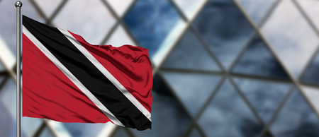 Trinidad And Tobago flag waving in the wind against blurred modern building. Business concept. National cooperation theme.の写真素材