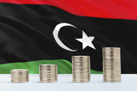 Libya flag waving in the background with rows of coins for finance and business concept. Saving money.の写真素材