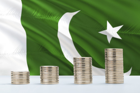 Pakistan flag waving in the background with rows of coins for finance and business concept. Saving money.の写真素材