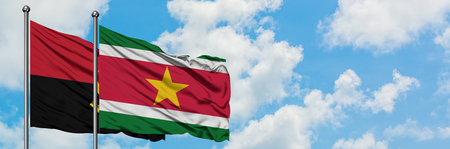 Angola and Suriname flag waving in the wind against white cloudy blue sky together. Diplomacy concept, international relations.の写真素材