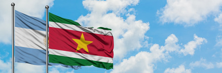 Argentina and Suriname flag waving in the wind against white cloudy blue sky together. Diplomacy concept, international relations.の写真素材