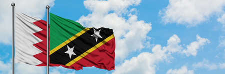 Bahrain and Saint Kitts And Nevis flag waving in the wind against white cloudy blue sky together. Diplomacy concept, international relations.の写真素材