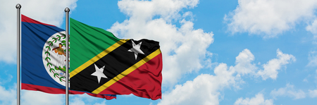 Belize and Saint Kitts And Nevis flag waving in the wind against white cloudy blue sky together. Diplomacy concept, international relations.の写真素材