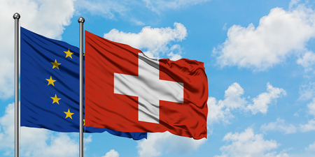 European Union and Switzerland flag waving in the wind against white cloudy blue sky together. Diplomacy concept, international relations.の写真素材