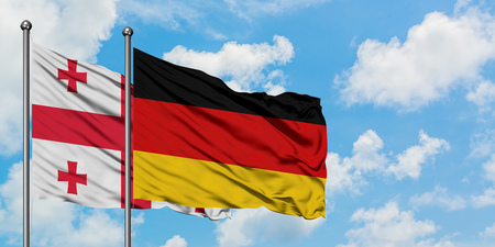 Georgia and Germany flag waving in the wind against white cloudy blue sky together. Diplomacy concept, international relations.の写真素材