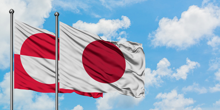 Greenland and Japan flag waving in the wind against white cloudy blue sky together. Diplomacy concept, international relations.の写真素材