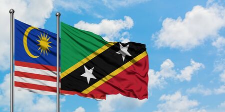 Malaysia and Saint Kitts And Nevis flag waving in the wind against white cloudy blue sky together. Diplomacy concept, international relations.の写真素材