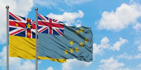 Niue and Tuvalu flag waving in the wind against white cloudy blue sky together. Diplomacy concept, international relations.の写真素材