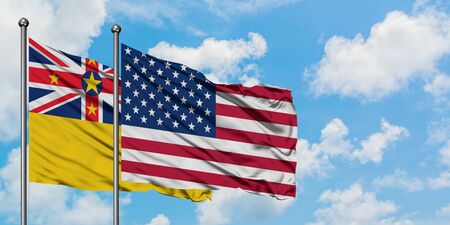 Niue and United States flag waving in the wind against white cloudy blue sky together. Diplomacy concept, international relations.の写真素材