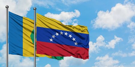 Saint Vincent And The Grenadines and Venezuela flag waving in the wind against white cloudy blue sky together. Diplomacy concept, international relations.の写真素材