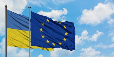 Ukraine and European Union flag waving in the wind against white cloudy blue sky together. Diplomacy concept, international relations.の写真素材