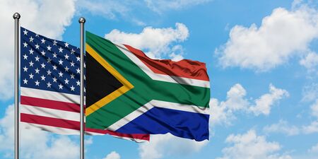 United States and South Africa flag waving in the wind against white cloudy blue sky together....