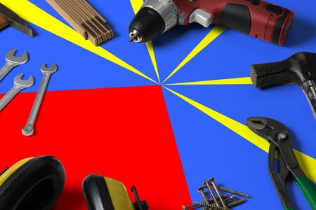 Reunion flag on repair tool concept wooden table background. Mechanical service theme with national...