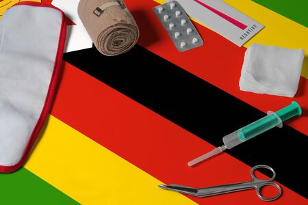 Zimbabwe flag with first aid medical kit on wooden table background. National healthcare system concept, medical theme.の写真素材