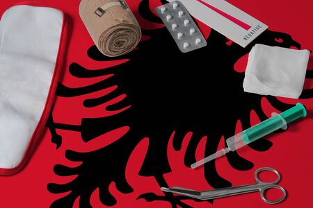 Albania flag with first aid medical kit on wooden table background. National healthcare system concept, medical theme.の写真素材