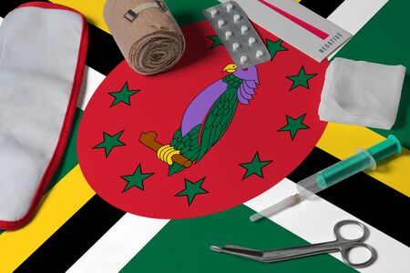 Dominica flag with first aid medical kit on wooden table background. National healthcare system concept, medical theme.の写真素材