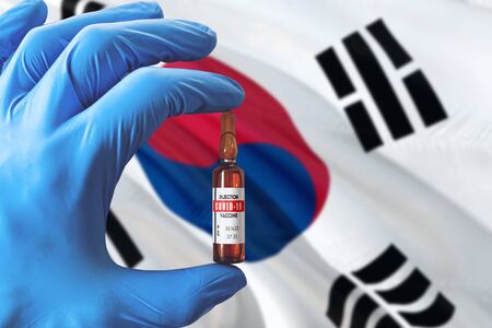 South Korea flag with Coronavirus Covid-19 concept. Doctor with blue protection medical gloves holding a vaccine bottle. Epidemic Virus, Cov-19, Corona virus outbreaking.の写真素材