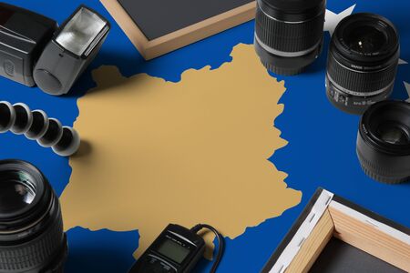 Kosovo national flag with top view of personal photographer equipment and tools on white wooden...