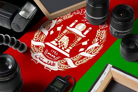 Afghanistan national flag with top view of personal photographer equipment and tools on white wooden...