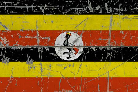 Uganda flag painted on cracked dirty surface. National pattern on vintage style surface. Scratched and weathered concept.の写真素材