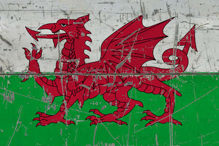 Wales flag painted on cracked dirty surface. National pattern on vintage style surface. Scratched and weathered concept.の写真素材