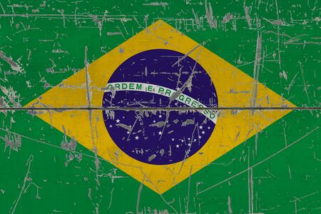 Brazil flag painted on cracked dirty surface. National pattern on vintage style surface. Scratched and weathered concept.の写真素材