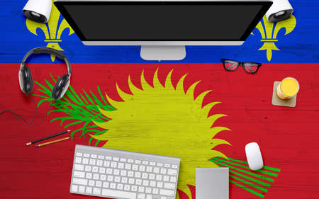 Guadeloupe flag background with headphone,computer keyboard and mouse on national office desk table.Top view with copy space.Flat Lay.の写真素材