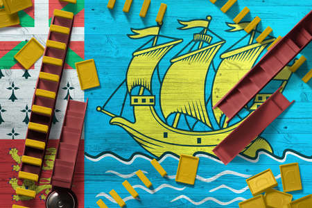 Saint Pierre And Miquelon flag with national background with dominoes on wooden table. Top view. Concept of game.の写真素材