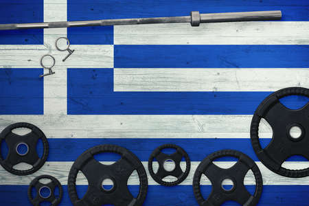 Greece gym concept. Top view of heavy weight plates with iron bar on national background.の写真素材