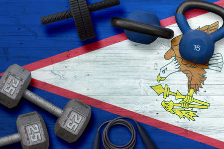 American Samoa sports club concept. Top view of heavy weight plates with iron bar on national background.の写真素材