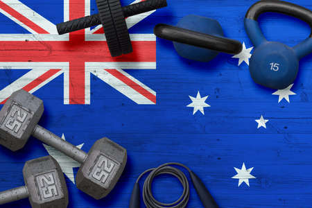 Australia sports club concept. Top view of heavy weight plates with iron bar on national background.の写真素材