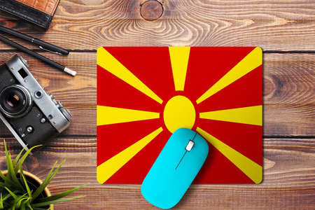 Macedonia flag on wooden background with blue wireless mouse on a mouse pad, top view. Digital media concept.の写真素材