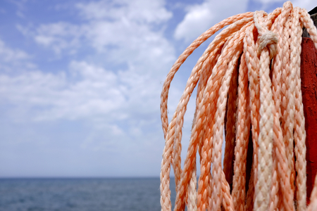 Skein of rope on the pole on the beach side for lifebuoy. The sea on background.の写真素材