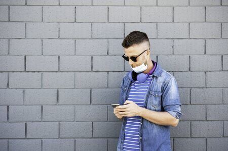Young man with headphones around his neck and lowered surgical mask after coronavirus outbreak -...