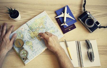 Male hand holding a magnifying glass for planning trip with world map on the table. Travel concept....