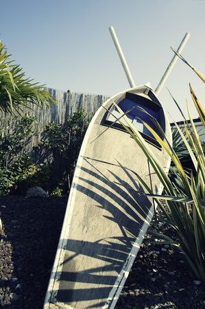 Wooden canoe leaning against the straw fence with paddles crossed. Vintage canoe against blue sky. Vertical. Copy space. Vacation and sport concept.の写真素材
