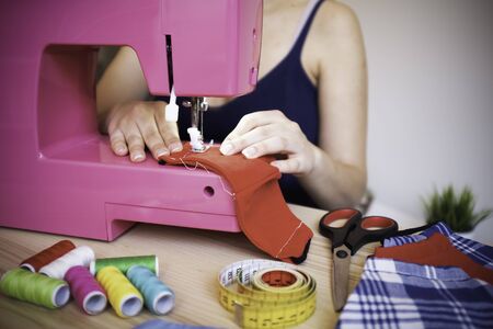 Seamstress working with sewing machine making trendy face medical mask for preventing and stop...