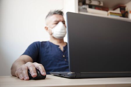 Portrait of man working at home or office with protective hygiene mask on his face. Pandemic and...