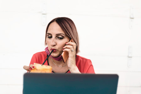 Smiling woman 40 years old wearing open protective face mask using laptop and cell phone during the end of coronavirus outbreak - Female entrepreneur working outdoors while make a healthy breakfastの写真素材