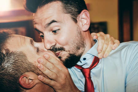 Loving gay couple kissing passionately at the wedding party - Two handsome men having romantic kiss indoors - LGBT wedding and rights conceptの写真素材